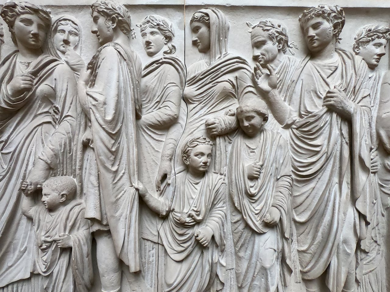 Intricate stone carving depicting ancient Roman figures in a museum setting.